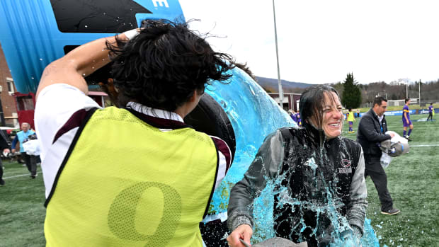 A player in a yellow pinnie dumps blue Powerade over coach Julianne Sitch